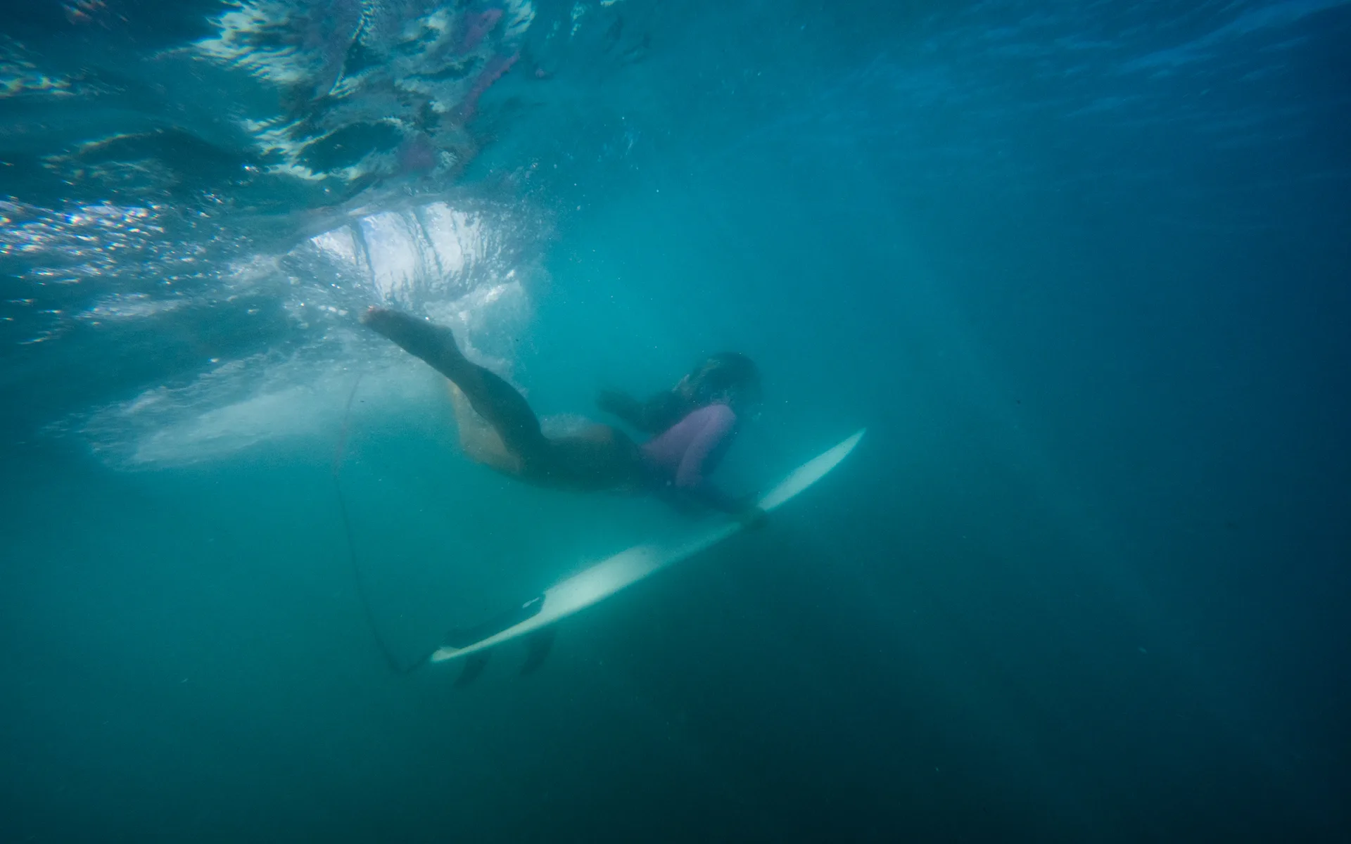 A surfer paddling beneath a wave off the Pacific coast