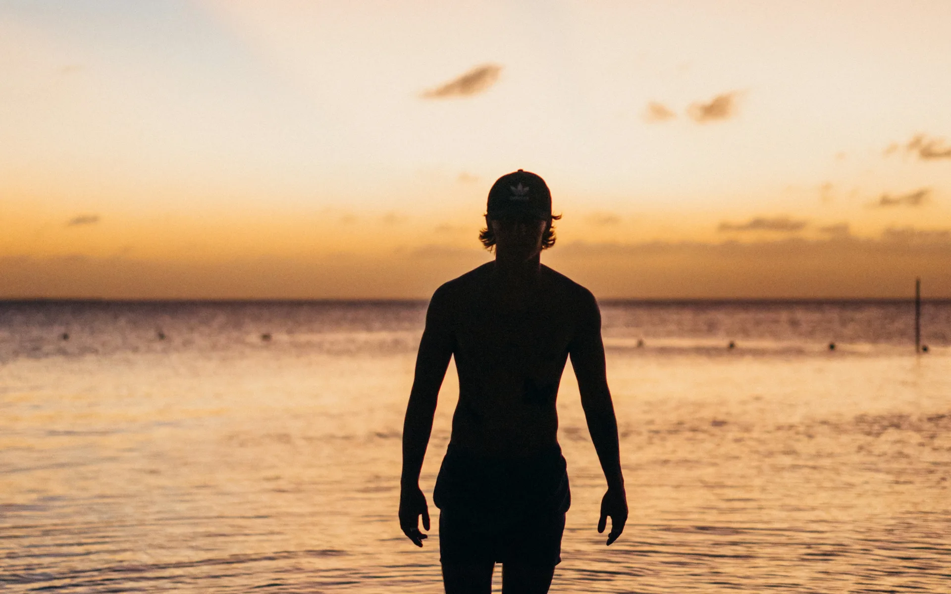 A silhouette walking into the sea at sunset