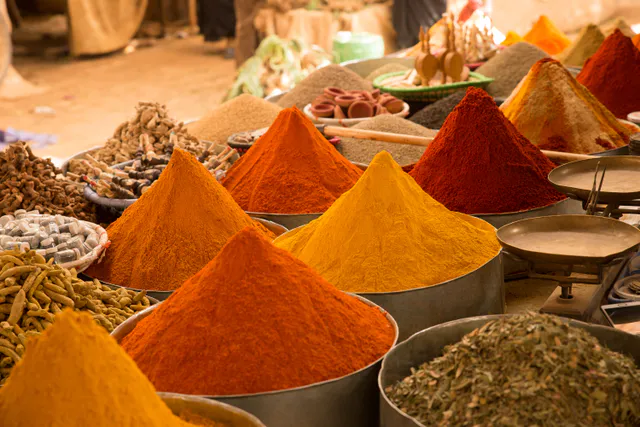 Cones of brightly coloured ground spices on a market stall.